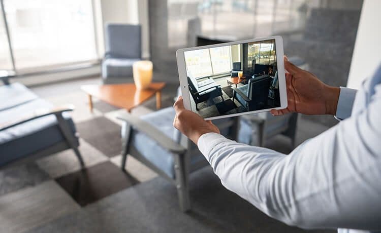 Immobilienkaufmann macht mit einem Tablet Fotos von einer Wohnung.