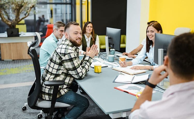 Betriebswirt sitzt mit Kollegen an einem Tisch und besprechen betriebswirtschaftliche Themen.