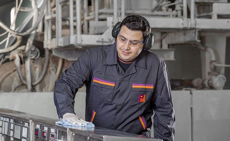 Gebäudereiniger bei Piepenbrock reinigt eine Maschine mit einem Lappen