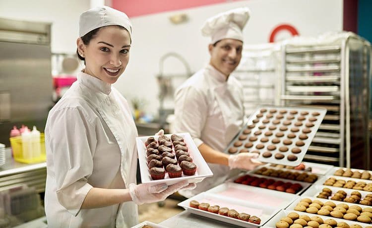 Junge Frau hält Pralinen in der Hand und steht in einer Küche.