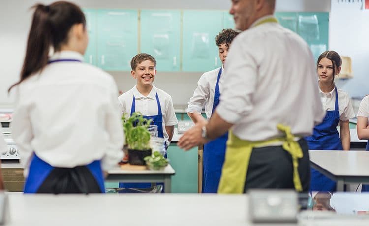 Ernährungsberater gibt einen Kochkurs an einer Schule und klärt Schüler über gesunde Ernährung auf.