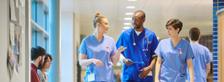 Gesundhets- und Krankenpflegehelfer gehen durch Krankenhausflur und unterhalten sich