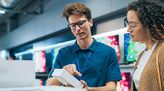 Verkäufer im Elektromarkt berät Kundin