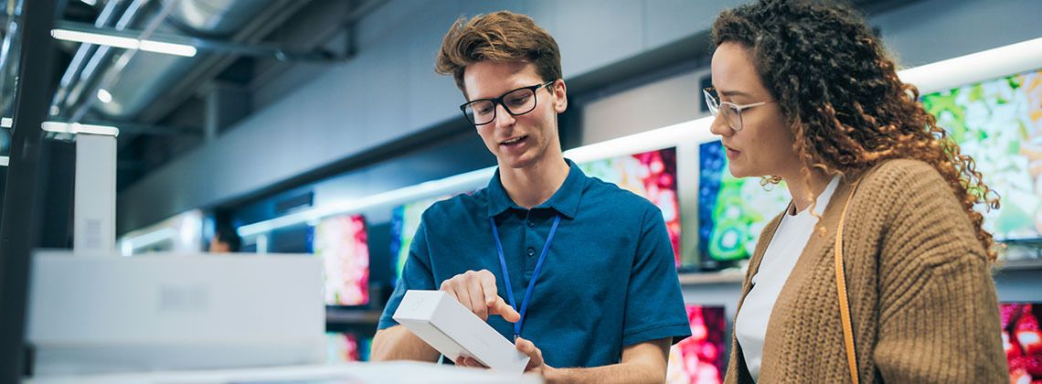 Verkäufer im Elektromarkt berät Kundin