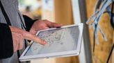 Hände mit Tablet, auf dem technische Systempläne zu sehen sind