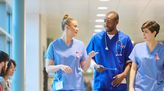 Gesundhets- und Krankenpflegehelfer gehen durch Krankenhausflur und unterhalten sich