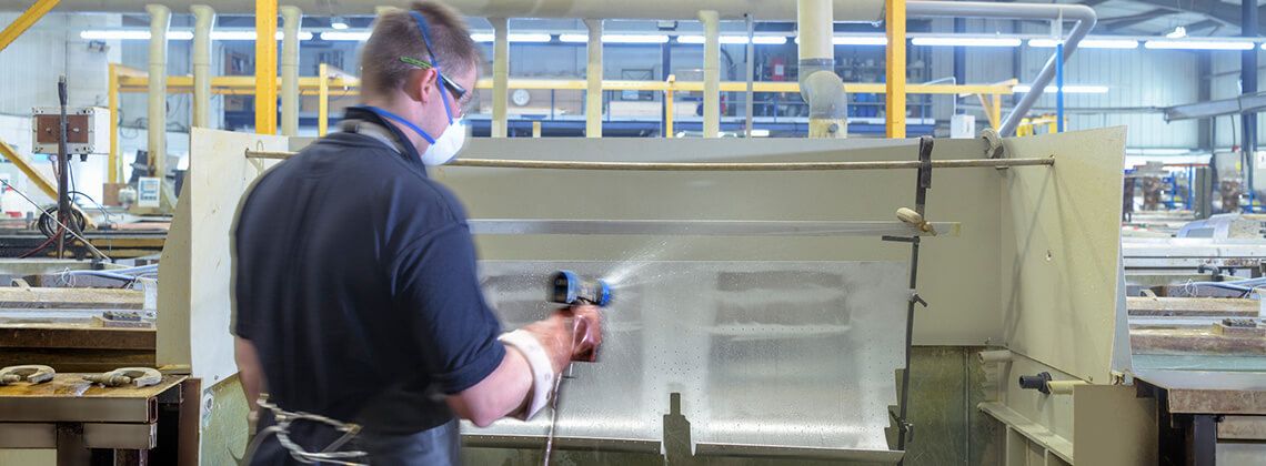 Oberflächenbeschichter besprüht Bauteil mit einer Pulverbeschichtung.