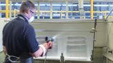 Oberflächenbeschichter besprüht Bauteil mit einer Pulverbeschichtung.