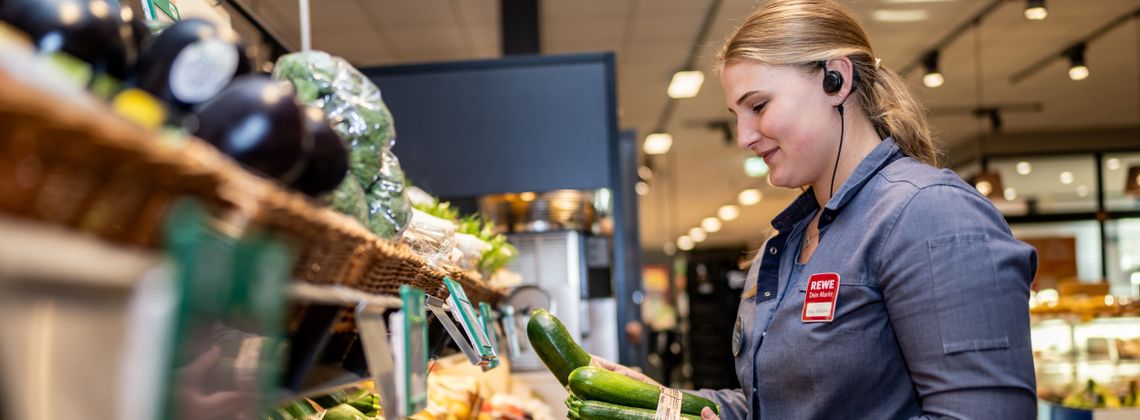 Kauffrau im EInzelhandel bei REWE bei der Arbeit an der Gemüsetheke.